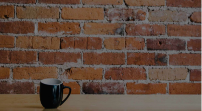 Black coffee mug on wooden surface with red brick wall background