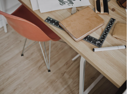 Light wood desk with coral chair, notebook, ruler, and pen in a tidy home workspace