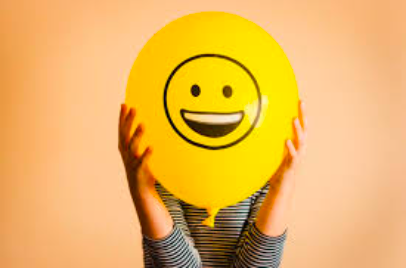 Person holding a yellow smiley-face balloon in front of their face