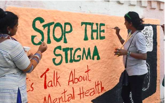 Two women painting a mural that reads 'Stop the Stigma, Let's Talk About Mental Health
