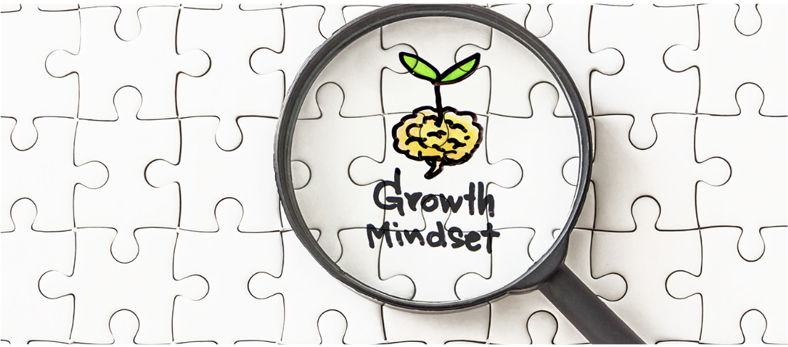 White jigsaw puzzle with magnifying glass highlighting a brain with sprouting leaves and handwritten 'Growth Mindset' text