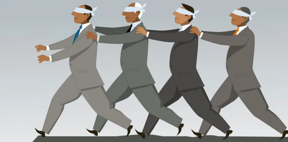 Four blindfolded businessmen in suits follow each other in a line toward the edge of a cliff, illustrating groupthink