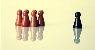 Four red game pawns grouped together facing a single black pawn, illustrating leadership separation and measurement