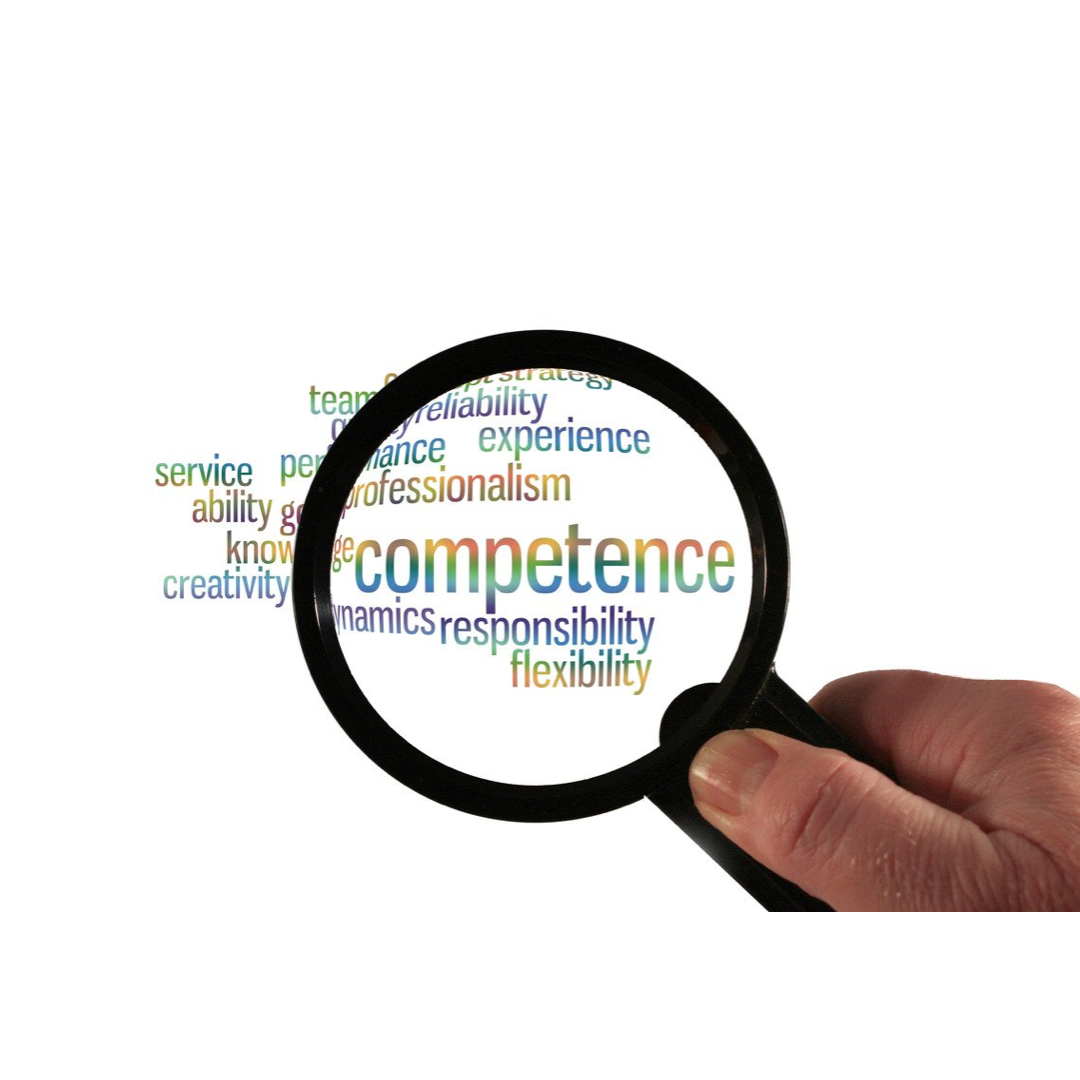 Hand holding magnifying glass over colorful word cloud centered on 'competence' with related workplace skills
