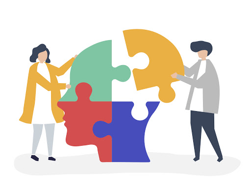 Two people assembling colorful puzzle pieces that form a human head silhouette