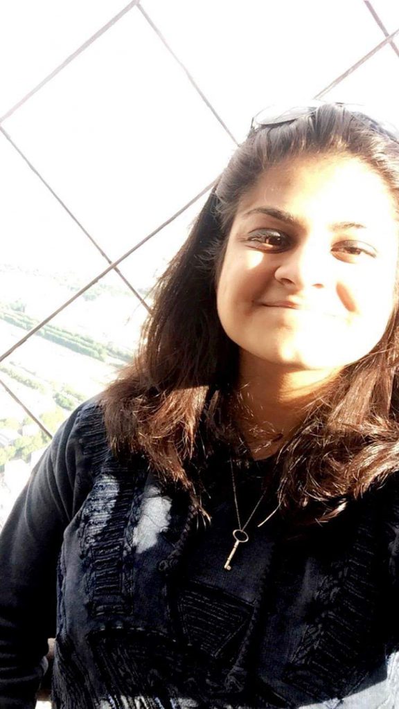 Devika Kapur Portrait of Devika Kapur, a psychology student, smiling near a window with diamond-patterned glass.